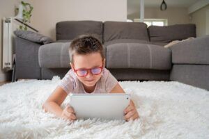 criança usando óculos ao mexer no tablet